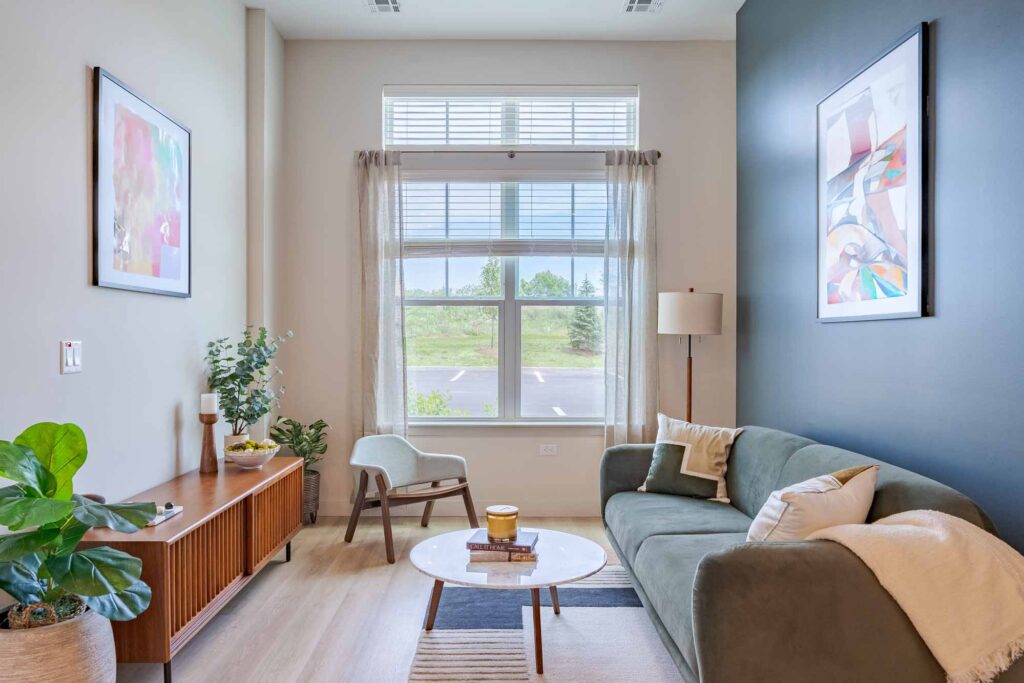 spacious living room with decor, art, open windows of natural light, sofa, table and an entertainment center at new apartments in Peabody, MA at Alexan Peabody.