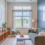 spacious living room with decor, art, open windows of natural light, sofa, table and an entertainment center at new apartments in Peabody, MA at Alexan Peabody.