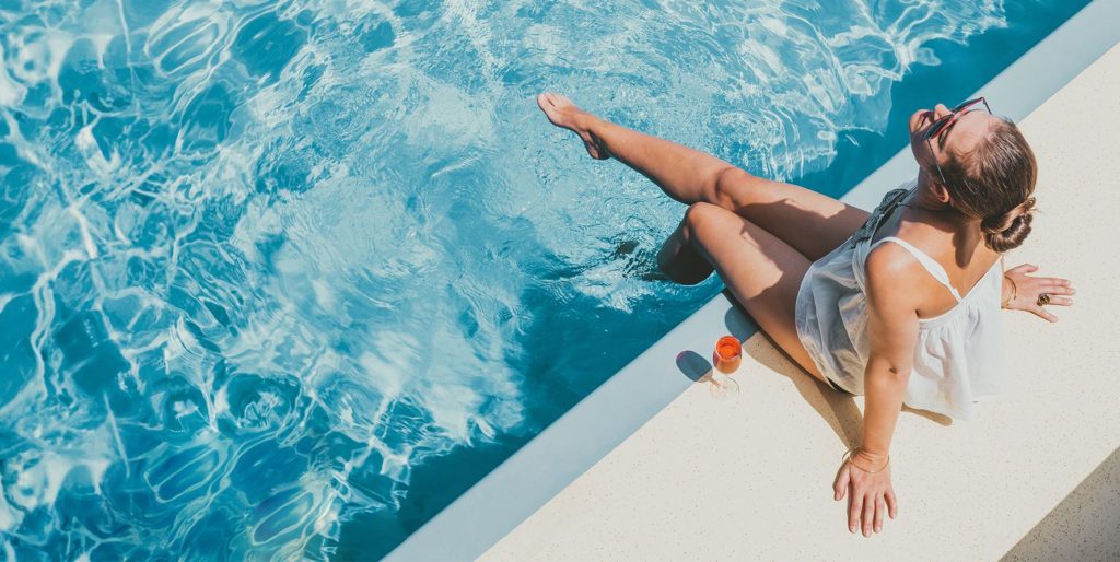 girl dipping foot into pool