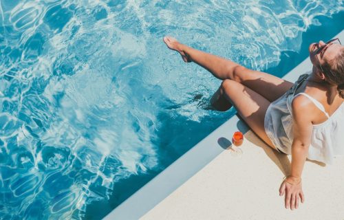 girl dipping foot into pool
