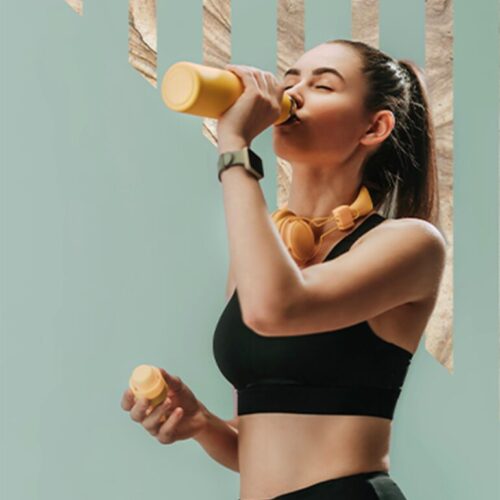 girl drinking orange water bottle wearing workout clothes.