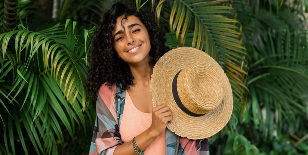 Alexan Peabody resident holding sun hat behind palms