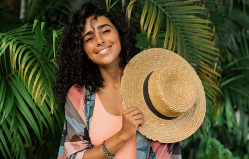 Alexan Peabody resident holding sun hat behind palms